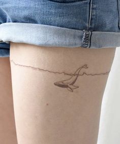 a woman's thigh with a whale tattoo on her leg and the bottom part of her thighs