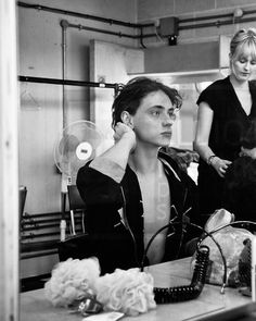 black and white photograph of two women in a hair salon, one holding her head to her ear