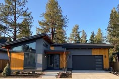 a house that is in the middle of some trees and has two garages on each side