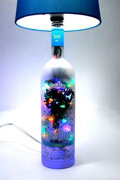 a bottle lamp with a blue shade on the side and a white background behind it