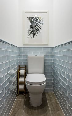 a white toilet sitting inside of a bathroom next to a wooden step case and tiled walls