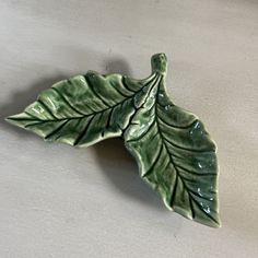 a green leaf shaped dish sitting on top of a table