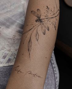 a woman's arm with a tattoo on it that has flowers and leaves drawn on it