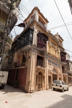 a car is parked in front of an old building with balconies on the second floor