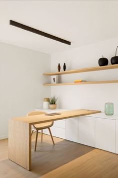 a wooden table sitting on top of a hard wood floor next to white shelves filled with potted plants