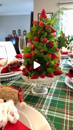 a christmas tree made out of strawberries on top of a table with plates and wine glasses