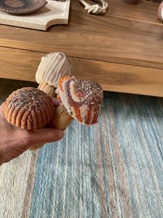 a person is holding two pastries in their hand on a rug near a coffee table