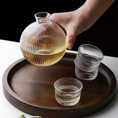 a person pouring water into two glasses on a tray