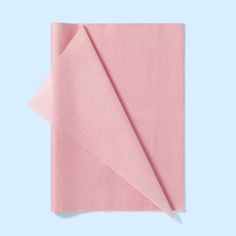 a pink napkin folded on top of a light blue background with the corner cut out