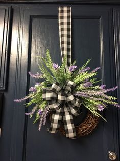 a wreath with purple flowers and greenery hangs on the front door's black door