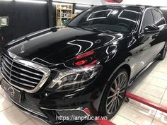 a black mercedes s - class is parked in a showroom with its hood up