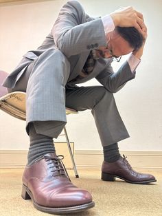 a man in a suit and tie sitting on a chair with his hands to his head