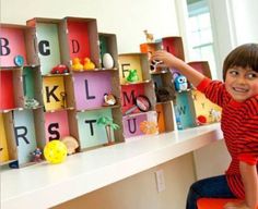 a young boy sitting on top of a desk holding a toy