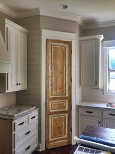 a kitchen with white cabinets and an old door in the center is empty except for someone to use it