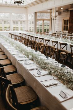 the long tables are set with place cards and place settings for guests to sit at