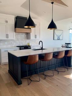 a kitchen with an island and three pendant lights hanging over it's counter tops