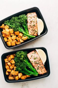 two black trays filled with food on top of a white counter next to each other