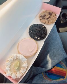 a box filled with assorted cookies sitting on top of a person's lap