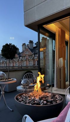 a fire pit sitting on top of a patio next to a tall building with lots of windows