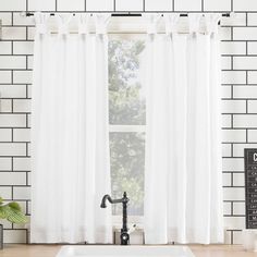 a kitchen sink sitting under a window next to a white tiled wall with a black faucet