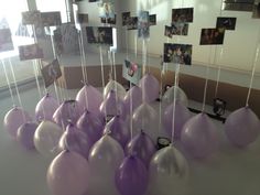 purple and white balloons hanging from the ceiling in a room with pictures on the wall