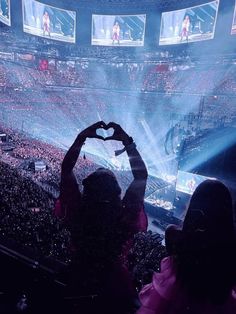 a person holding up a heart in front of a crowd at a concert or show