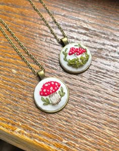 These beautiful hand embroidered wild mushroom necklaces make the perfect gift for a loved one or for mushroom lovers! All hand embroidered and set on a bronze gold pendant with chain. Please select which style you would like by choosing the above option. Only one style of each is available. When they're gone they're gone! For more information please send a direct message x Mushroom Necklaces, Hand Embroidered Pendant, Hand Embroidered Necklace, Hand Embroidered Jewelry, Embroidered Pendant, Embroidery Necklace, Mushroom Necklace, Wild Mushroom, Embroidered Necklace