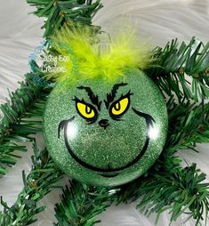 a green ornament with yellow eyes and a grin face painted on it's side