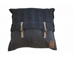 a black and grey pillow with two straps on the front, sitting on a white surface