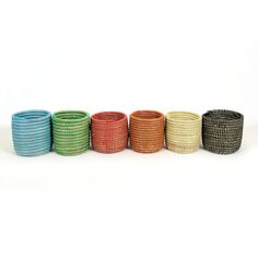 six different colored woven bracelets are lined up in a row on a white background