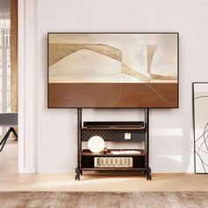 a living room with white walls and wooden flooring is pictured in this image, there are two framed art pieces on the wall