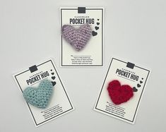 three small crocheted hearts are on the card for sale in this package, one is blue and one is red