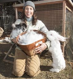 a woman sitting on the ground holding a basket filled with fluffy white rabbits in it