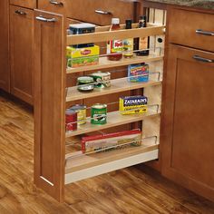 a pull out spice rack in the middle of a kitchen with wood floors and cabinets