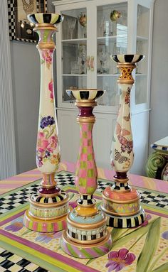 three colorful vases sitting on top of a table next to each other in front of a china cabinet