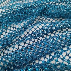 a close up view of a blue netted material with holes in the center and sides