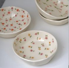 three bowls with floral designs on them sitting on a counter top next to each other