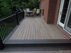 a wooden deck with black railing and chairs