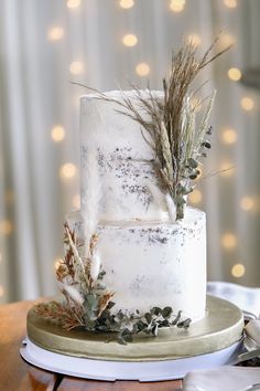 a wedding cake with white frosting and greenery