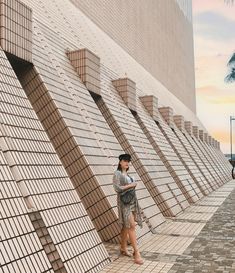 a woman standing next to a wall looking at her cell phone