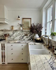 a kitchen with marble counter tops and white cabinets, along with an island style sink