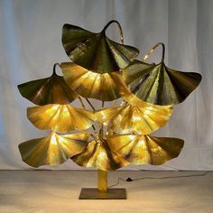 a lamp that is sitting on top of a wooden base and has leaves attached to it