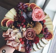 a platter filled with cheese, fruit and flowers