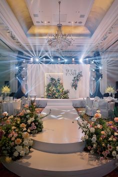 a wedding ceremony setup with flowers on the stage and chandelier above it,