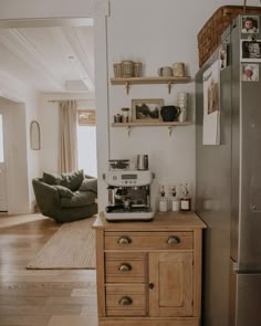 a coffee maker on top of a wooden cabinet next to a refrigerator in a living room