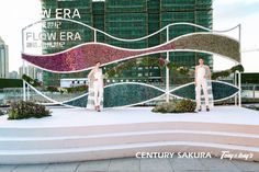 two mannequins are standing in front of a large sign with flowers on it