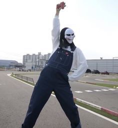 a person wearing a mask and overalls is standing in the street