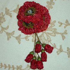 two red flowers on a white and beige table cloth with green beads hanging from the center