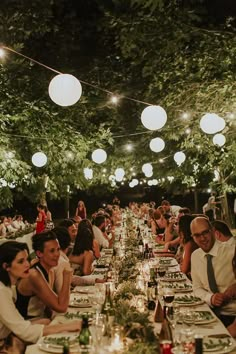 a group of people sitting at a long table with plates and wine glasses on it