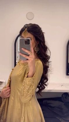 a woman taking a selfie in front of a mirror wearing a gold dress and holding a cell phone